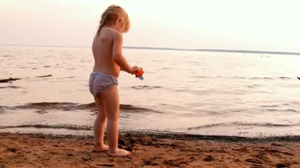 Kleines Mädchen spielt, blickt weit aufs Wasser — Stockvideo