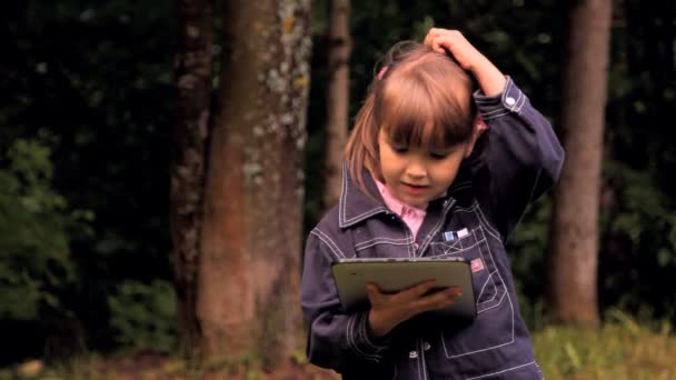 Niña juega con una tableta, el portátil, el netbook, iPad — Vídeos de Stock