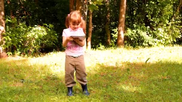 Bambina gioca con un tablet, il computer portatile, il netbook, iPad — Video Stock