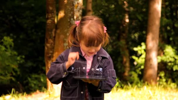 Bambina gioca con un tablet, il computer portatile, il netbook, iPad — Video Stock