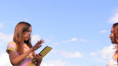 Two girls play work with a tablet, iPad, the laptop