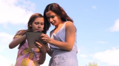 Two girls play work with a tablet, iPad, the laptop
