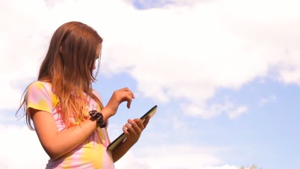 A menina, o adolescente brinca, trabalha com um tablet, iPad — Vídeo de Stock