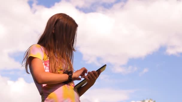 A menina, o adolescente brinca, trabalha com um tablet, iPad — Vídeo de Stock