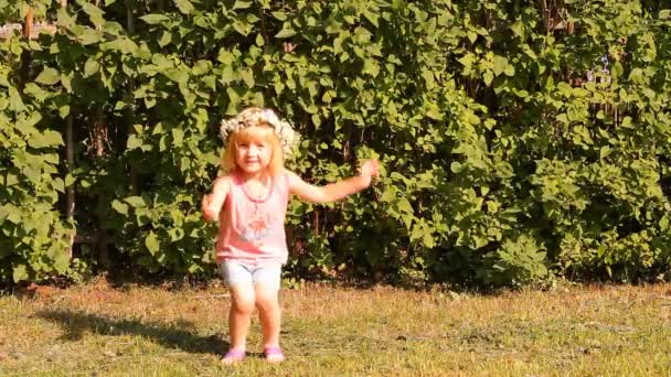 The girl in a wreath from camomiles of flowers plays — Stock Video