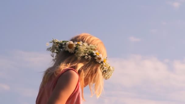 Das Mädchen im Kranz aus Kamillenblüten spielt mit einem Ball — Stockvideo