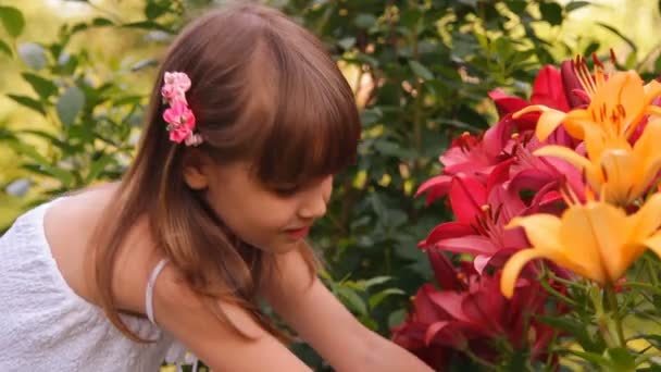 Het meisje onder lelies, bloemen glimlacht golven een hand — Stockvideo