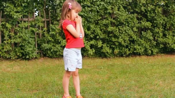 Girl eating an apple outdoors, summer, green grass — Stock Video