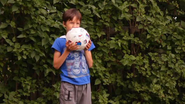 Pojken spelar en boll utomhus — Stockvideo