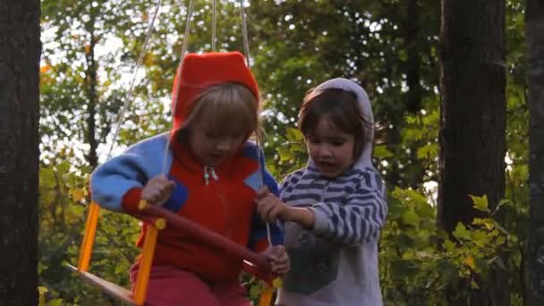 Two girls playing, laughing on a swing — Stock Video