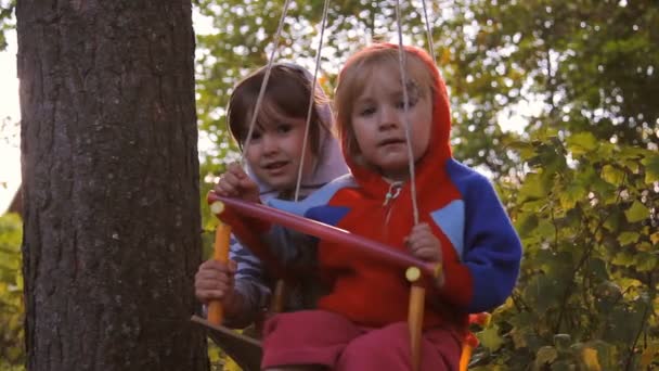 Dvě dívky hrát, směje se na houpačce — Stock video