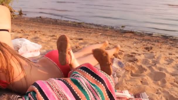 Девушка кладет одеяло на пляж рядом с сестрой — стоковое видео