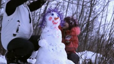 kadın (anne) ve kardan adam ile oynayan küçük bir kız