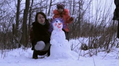 kadın (anne) ve kardan adam ile oynayan küçük bir kız