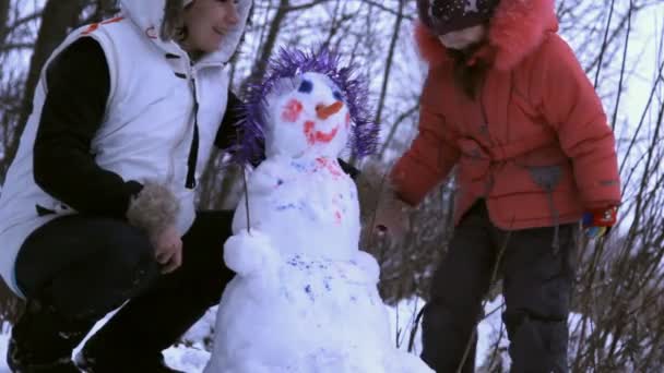 Kvinna (mor) och en liten flicka som leker med snögubbe — Stockvideo