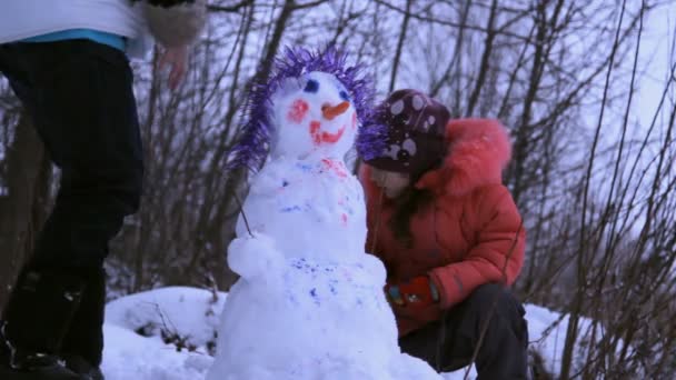 Mujer (madre) y una niña jugando con muñeco de nieve — Vídeo de stock