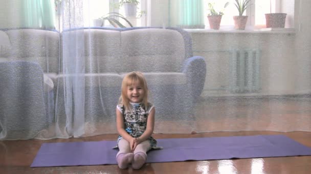 Маленькая девочка играет дурака, делает упражнения, йогу — стоковое видео