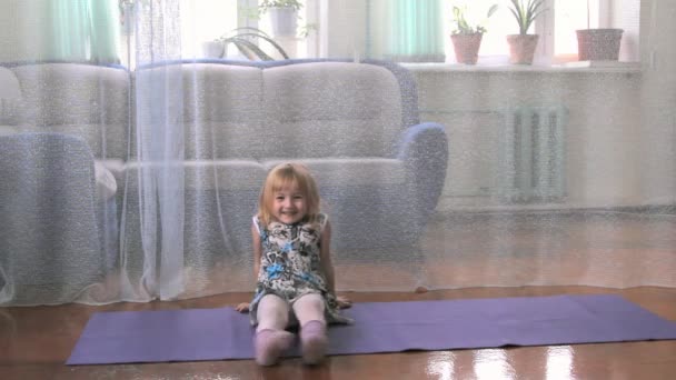 A little girl plays the fool, doing exercises, yoga — Stock Video