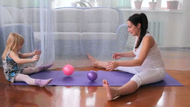 Una niña y una mujer embarazada hacen ejercicios, yoga, juegan con una pelota — Vídeo de stock