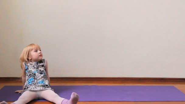 A little girl plays the fool, doing exercises, yoga — Stock Video