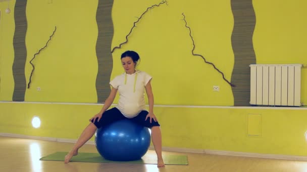 Беременная женщина делает упражнения с мячом, йогой — стоковое видео