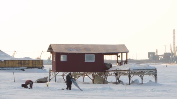 Pêche hivernale sur fond de cheminées d'usine, grues — Video