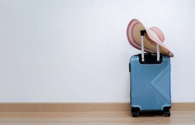                                Tekerlekli çanta, beyaz arka planda hasır şapka.