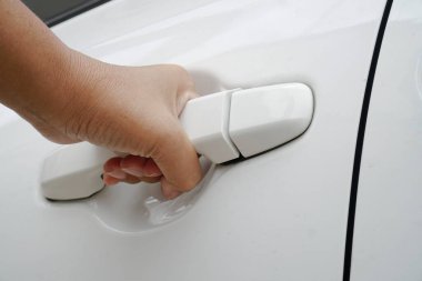 Kadının eli beyaz arabanın kapısını açar. Kapat..