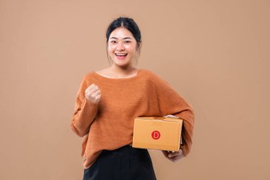 Teslimat kuryesi ve nakliye hizmeti konsepti. Kahverengi ekran arka planında izole edilmiş paket kutuları tutan mutlu Asyalı kadın. 