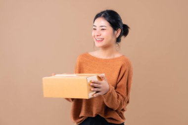 Teslimat kuryesi ve nakliye hizmeti konsepti. Kahverengi ekran arka planında izole edilmiş paket kutuları tutan mutlu Asyalı kadın. 