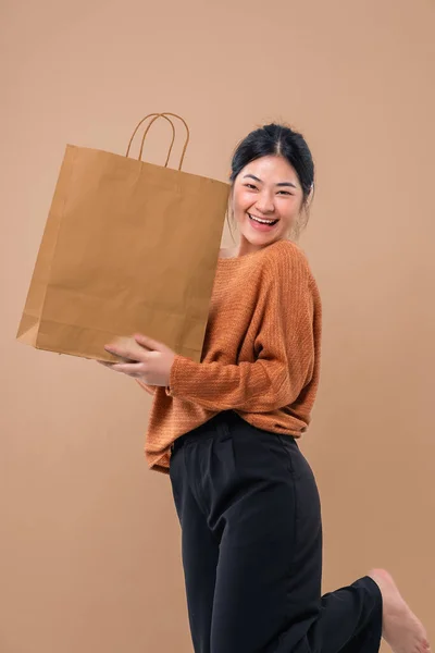 Happy Asian woman holding paper shopping bags enjoying shopping.