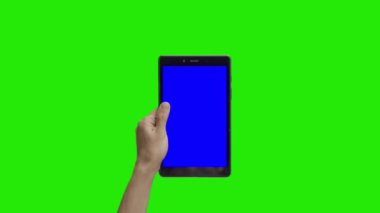 Tablet in the hand close up isolated at green background. Tablet screen is blue chroma key, background chroma key green screen. Footage for Tablet ads, app promo.
