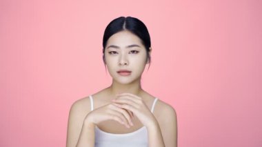 Güzel Asyalı kızın pembe arka planda izole edilmiş kameraya bakışının güzel bir görüntüsü..