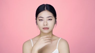 Genç ve güzel Asyalı bir kadının mükemmel güzelliği yüzüne parmak uçlarıyla nazikçe masaj yapıyor. Yüz kremi reklam konsepti.