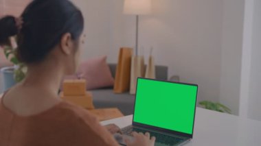 Ofiste çalışan bir iş kadınının omuz üstü fotoğrafı. Masanın üstünde, yeşil ekrana bakıyor. Laptop yeşil ekranlı dizüstü bilgisayar kullanan kişi.