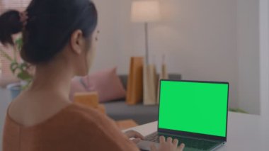 Ofiste çalışan bir iş kadınının omuz üstü fotoğrafı. Masanın üstünde, yeşil ekrana bakıyor. Laptop yeşil ekranlı dizüstü bilgisayar kullanan kişi.