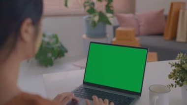 Ofiste çalışan bir iş kadınının omuz üstü fotoğrafı. Masanın üstünde, yeşil ekrana bakıyor. Laptop yeşil ekranlı dizüstü bilgisayar kullanan kişi.