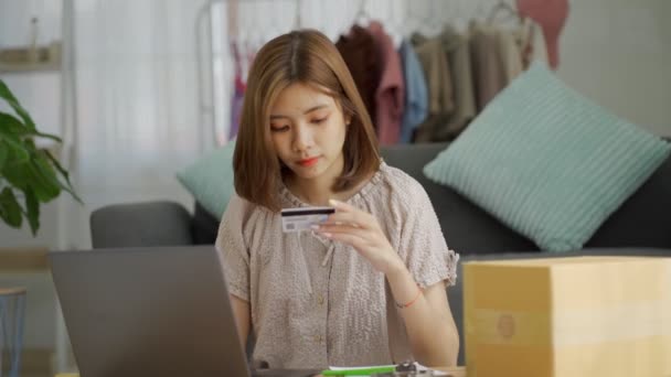 持有信用卡和智能手机的年轻女性顾客坐在家里的沙发上 快乐的女性购物者在网上商店里使用即时方便的移动支付购买 电子银行应用软件服务 — 图库视频影像