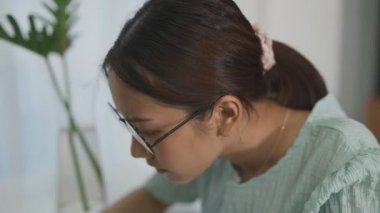 Ofiste işten dolayı stres hisseden Asyalı bir kadın. Ofiste çalışan yorgun bir iş kadını başını ellerinin üzerinde tutarken baş ağrısı hisseder..