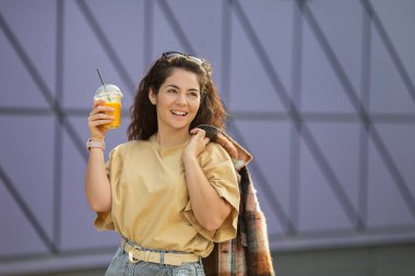 Kıvırcık saçlı, gülümseyen, şık bir kadın.