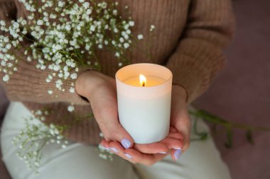 Elinde yanan mum tutan kadın. Kadın eli ve mum yakın çekim.