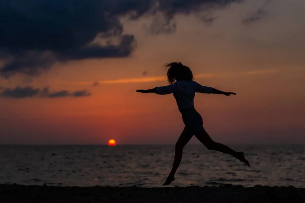 Mujer joven feliz divirtiéndose con las manos abiertas al atardecer en el mar. — Foto de Stock