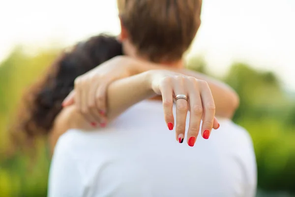 Egy fiatal romantikus pár ölelkezik és csókolózik. A nő megöleli a férfit, a női kézre koncentrál. Család és boldogság fogalma. — Stock Fotó