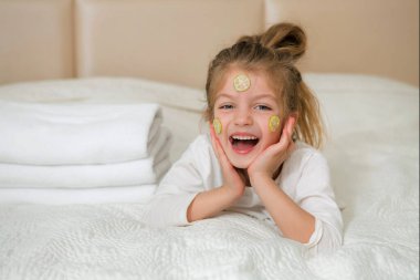 Gülümseyen mutlu bir kız çocuğunun portresi. 5 yaşındaki tatlı kız yatakta dinleniyor. Cilt bakımı kavramı.