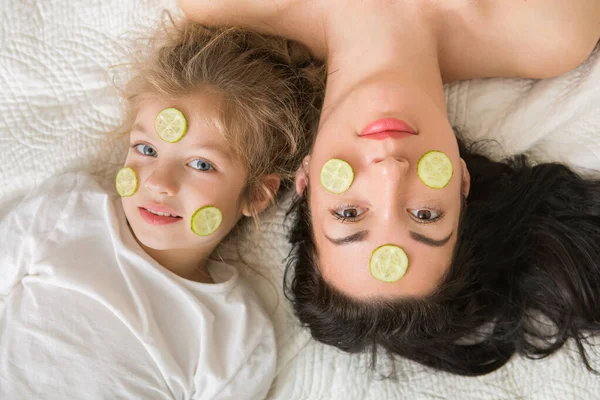 Anne ve kızı yatakta oynuyorlar ve sarılıyorlar. Sevgi dolu bir aile. Anneler günün kutlu olsun..