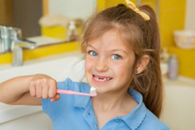 Banyoda dişlerini fırçalayan güzel küçük bir kız. Çocuklar için sağlıklı konsept ve diş sağlığı.