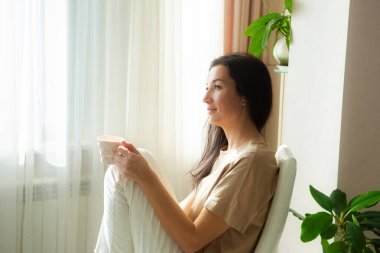 Çekici genç bir kadın kahve içip evde dinleniyor..