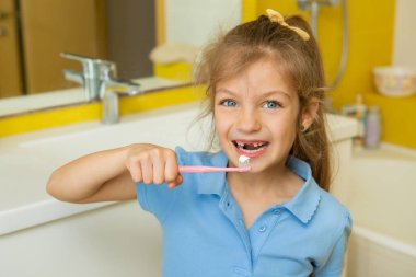 Banyoda dişlerini fırçalayan güzel küçük bir kız. Çocuklar için sağlıklı konsept ve diş sağlığı.