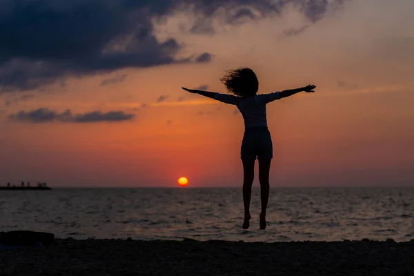 幸せな若いです女性とともに楽しいですオープン手で海の上の夕日. — ストック写真