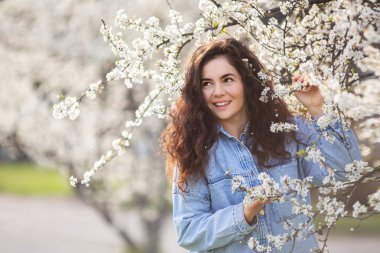 Bahar çiçekleriyle güzel mutlu bir kız. Açık havada gülümseyen esmer kadının portresi..